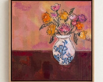 Puede incluir: Un cuadro cuadrado enmarcado que muestra un jarrón blanco con motivos florales azules que contiene un ramo de flores naranjas y rosas de trazo expresivo. El fondo es una mezcla de tonos rosa suave y granate oscuro, con un estilo pictórico.