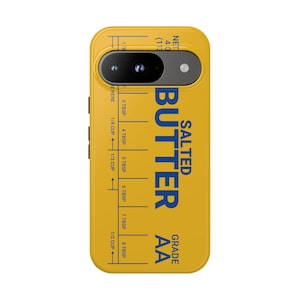 May include: Yellow phone case with a design resembling a stick of butter. The case features the words "SALTED BUTTER" in blue, along with measurement markings and the text "GRADE AA".