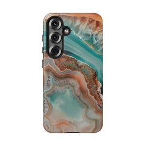 May include: A phone case with a colorful agate pattern in shades of brown, orange, and blue. The case has a cutout for a triple camera lens.