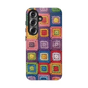 May include: A phone case with a vibrant patchwork design. The case is covered in a grid of crocheted squares in various colours, including red, yellow, green, blue, and purple. The phone's camera lenses are visible.