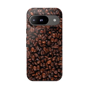 May include: A phone case with a pattern of roasted coffee beans. The case is dark brown with a glossy finish, and the camera lens is visible at the top. The design gives the appearance of a fresh coffee bean texture.