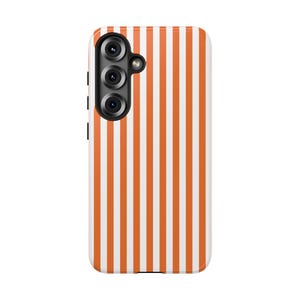 Op de afbeelding: Telefoonhoesje met verticale oranje en witte strepen. De hoes heeft een drievoudige cameralens en een flitser. De hoes is ontworpen voor een smartphone en heeft een glanzende afwerking.