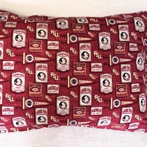 May include: A rectangular pillowcase with a maroon background, patterned with various Florida State University logos and emblems in white, gold, and maroon. The pillowcase is rectangular and rests on a white surface.
