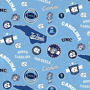 May include: Light blue fabric featuring a repeating pattern of North Carolina Tar Heels logos, text, and imagery. The design includes the words "Carolina," "Tar Heels," and "UNC," along with footballs, ram mascots, and the state outline.