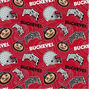 May include: Red patterned fabric featuring Ohio State Buckeyes logos, helmets, and the word "Buckeyes." The design includes the Ohio State logo, a cartoon mascot, and football helmets in a repeating pattern.