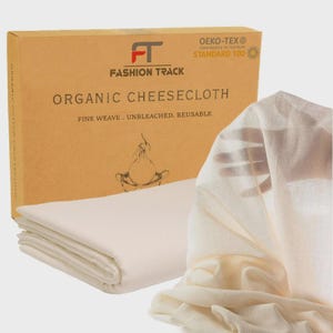 May include: Off-white organic cheesecloth, folded and stacked, beside a brown box. The box reads "FASHION TRACK ORGANIC CHEESECLOTH" and "FINE WEAVE. UNBLEACHED. REUSABLE." The cheesecloth is made of organic cotton.