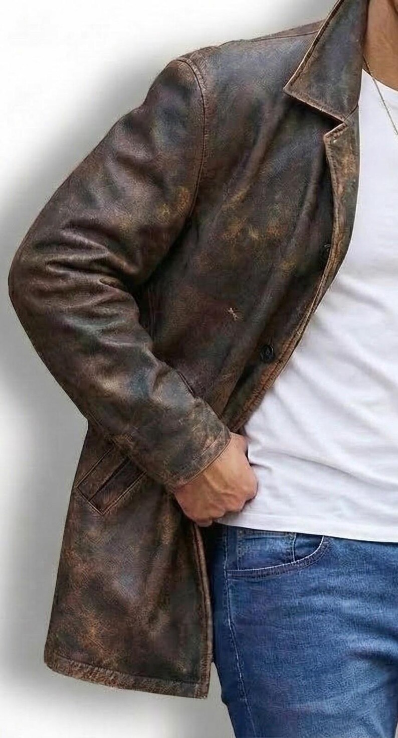 May include: A distressed brown leather jacket with a classic lapel collar and a single-button closure. The jacket has a worn, textured appearance, suggesting a vintage or rugged style. The model is wearing a white t-shirt and blue jeans.