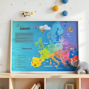 May include: A framed map of Europe with a white border, featuring colorful country outlines and the text "Elena's Europe." The map includes illustrations of landmarks and geographical features. A toy airplane and decorative hanging spheres are above the frame.