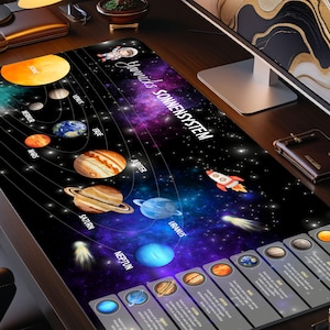 May include: A rectangular desk mat featuring a colorful illustration of the solar system. The design includes planets, a rocket, and the text "Yannicks Sonnensystem". The mat is on a wooden desk with a lamp and a monitor.