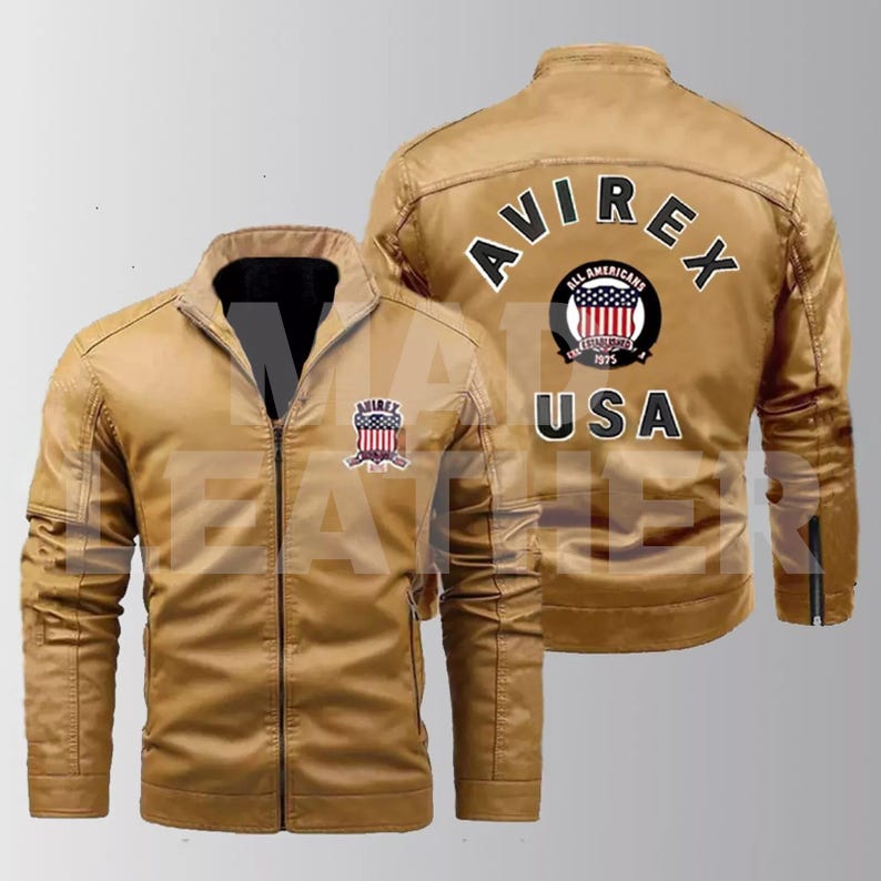 May include: A tan leather jacket with a zipper closure. The jacket has a patch on the left chest with the text "AVIREX" and a small American flag. The back of the jacket has a large patch with the text "AVIREX" in a circle with an American flag and the text "ALL AMERICANS" and "USA".