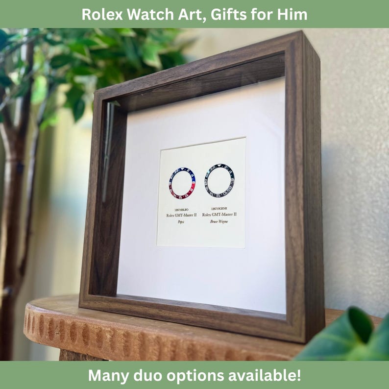 May include: A framed artwork with two Rolex watch dial designs, incorporating red, white, and blue. The piece is set in a dark wooden frame with a white mount. The text at the top reads "Rolex Watch Art, Gifts for Him". The bottom text says "Many duo options available!"