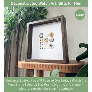 Puede incluir: Una obra de arte enmarcada con piezas de reloj deconstruidas. La obra de arte se muestra en un marco de madera marr&oacute;n oscuro, con un paspart&uacute; blanco. La imagen incluye engranajes de reloj, esferas y otros componentes. El marco mide 25,4 x 25,4 cm. El texto en la parte superior dice "Deconstructed Watch Art, Gifts for Him."