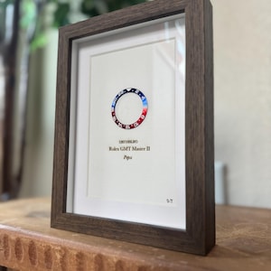 May include: Framed print featuring a Rolex GMT Master II "Pepsi" bezel design. The bezel is red and blue, with white text and numbers. The frame is dark brown, and the print includes the model number and "Pepsi" text.