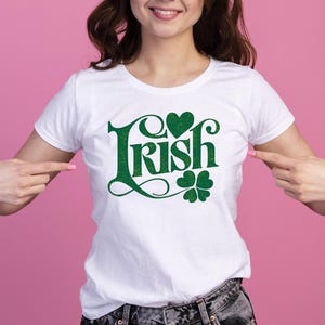 May include: White t-shirt with a green shamrock and heart design and the text "Irish" in a green script font.