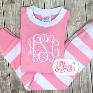 Puede incluir: Pijama a rayas rosa y blanco con un monograma blanco en la parte delantera. El pijama tiene un cuello y pu&ntilde;os acanalados blancos. El texto "Miss Sew It All" es visible en la esquina inferior derecha de la imagen.