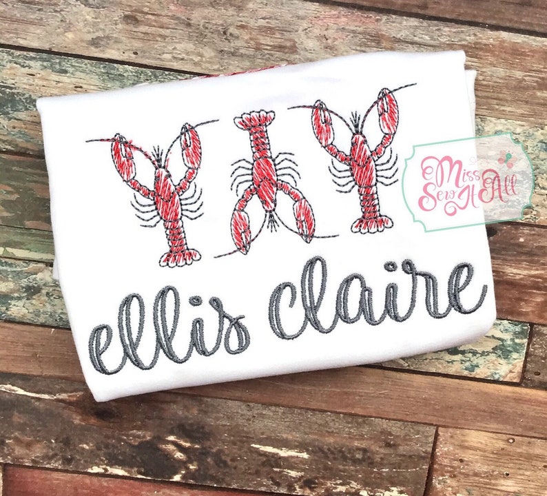 May include: White t-shirt with three red embroidered lobsters and the text "ellis claire" in gray cursive.