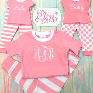 Puede incluir: Pijama a rayas rosa y blanco con un monograma blanco en la camisa. El pijama es para un ni&ntilde;o y tiene las palabras "Holly" y "Baby" en las camisas.