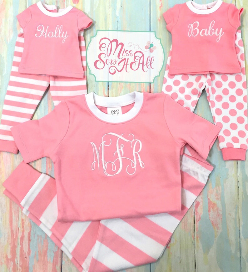 Puede incluir: Pijama a rayas rosa y blanco con un monograma blanco en la camisa. El pijama es para un ni&ntilde;o y tiene las palabras "Holly" y "Baby" en las camisas.