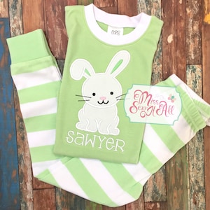 May include: Green and white striped pajamas with a white bunny applique and the name "Sawyer" embroidered on the front. The pajamas are made by Miss Sew It All.