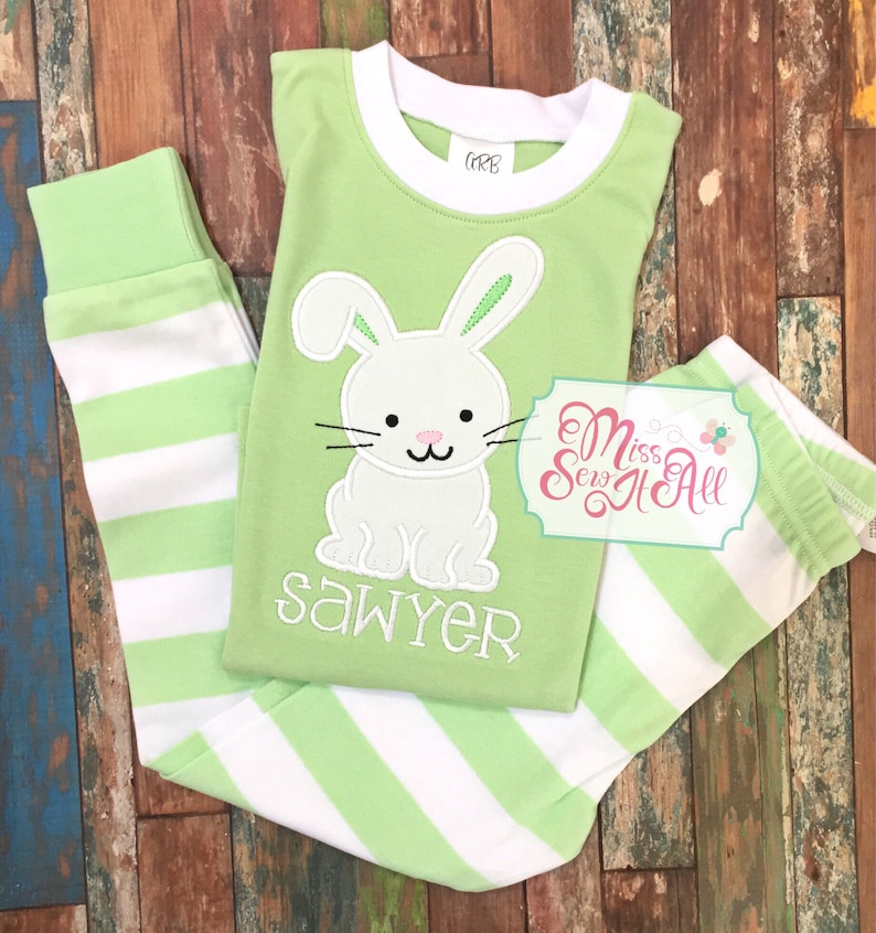 May include: Green and white striped pajamas with a white bunny applique and the name "Sawyer" embroidered on the front. The pajamas are made by Miss Sew It All.