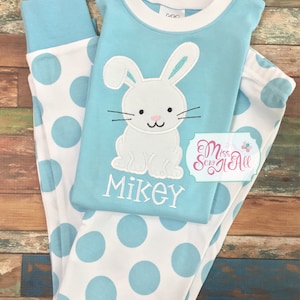 May include: Blue and white polka dot pajamas with a white bunny applique on the top. The bunny has pink ears and a black nose. The top also has the name "Mikey" embroidered on it.