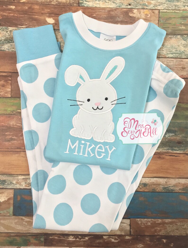 May include: Blue and white polka dot pajamas with a white bunny applique on the top. The bunny has pink ears and a black nose. The top also has the name "Mikey" embroidered on it.