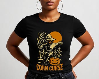 Könnte beinhalten: Schwarzes T-Shirt mit einem Halloween-Motiv. Die Grafik zeigt eine Vogelscheuche, einen geschnitzten Kürbis und den Text "Corn Curse" in Orange. Ein orangefarbener Mond ist im Hintergrund. Die Vogelscheuche trägt einen Hut.