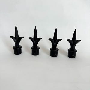 Peut inclure: Un ensemble de quatre embouts de tringle à rideaux noir mat, chacun présentant un design en forme de pointe de lance avec une base évasée et un petit trou de vis circulaire sur le côté du collier de montage cylindrique pour la fixation.