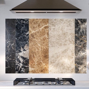 Könnte beinhalten: Eine Küchenrückwand mit vier Paneelen mit verschiedenen Marmormustern. Die Paneele sind schwarz-weiß, braun-weiß, beige-weiß und schwarz-gold. Die Rückwand ist hinter einem Edelstahl-Kochfeld installiert.