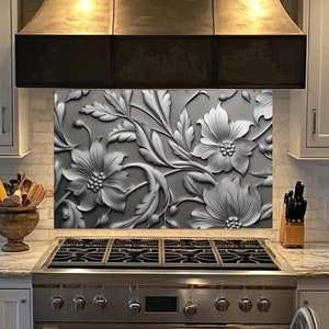 May include: A stainless steel stovetop with five burners and a matching oven. The stovetop has a decorative backsplash with a silver floral design.