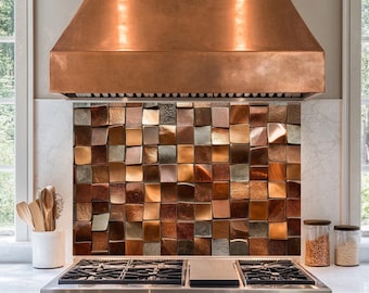May include: A stainless steel range with a copper range hood and a copper tile backsplash. The range has four burners and a griddle.