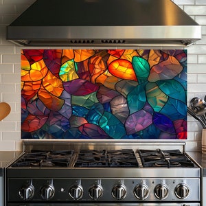 May include: A colorful stained glass backsplash with a variety of colors, including red, orange, yellow, green, blue, purple, and brown. The backsplash is installed above a stainless steel stove with a black cooktop.