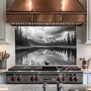 May include: Black and white photograph of a mountain lake with a reflection of the mountains in the water. The image is printed on a glass backsplash for a stove.