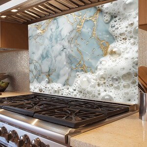 May include: A kitchen backsplash with a marble design featuring white and blue swirls with gold accents. The bottom of the backsplash has a white foam design with large and small bubbles.