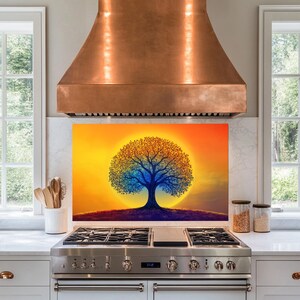 May include: A colourful abstract tree with blue, orange and yellow hues is silhouetted against a sunset backdrop. The tree is centred on a kitchen backsplash with a copper range hood above.