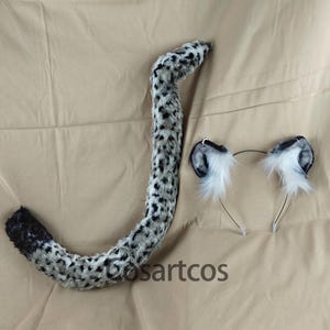 May include: A grey and black spotted faux fur tail with a black tip and a matching headband with grey and black spotted faux fur ears.