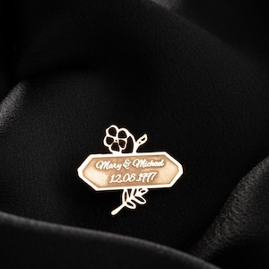 May include: A gold-toned metal wedding anniversary ornament with a floral design and the text "Mary & Michael 12.08.1977".