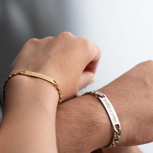 Puede incluir: Dos pulseras de oro y plata con números romanos grabados y un nombre en las bandas.
