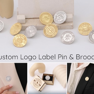 May include: Assortment of custom logo label pins and brooches in gold, silver, and black metal. The pins feature various designs, including a fish, a coffee cup, a flamingo, and a football team logo. The pins are displayed on a white surface.