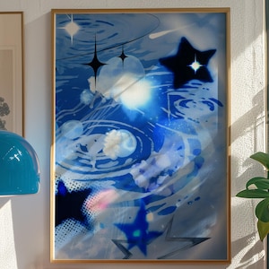 May include: Abstract art print featuring a blue and white celestial design with stars and swirling patterns. The artwork is framed in a gold-colored frame and hangs on a white wall. The image is part of a home decor theme.