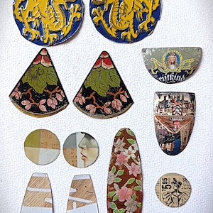 May include: A collection of various vintage metal embellishments. Includes two blue and yellow dragon medallions, floral and geometric shapes, and circular pieces with text and illustrations. A ruler is at the top.