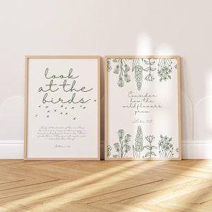 May include: Two framed art prints with light wood frames. The left print says "look at the birds" with a flock of birds and a Bible verse. The right print says "Consider how the wildflowers grow" with floral illustrations and a Bible verse.