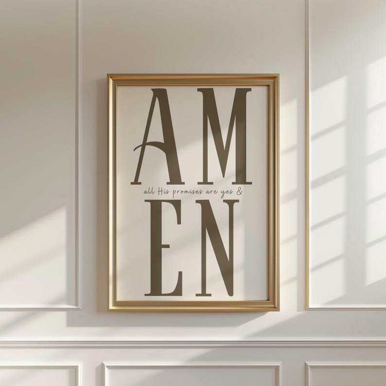 May include: A framed print with the word "AMEN" in large, dark brown letters. Below, smaller text reads "all His promises are yes &". The frame is gold, and the background is off-white.