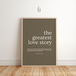Może przedstawiać: Oprawiony wydruk z brązowym tłem i białymi słowami "the greatest love story". Poniżej, w mniejszej czcionce wydrukowany jest werset biblijny z Jana 3:16. Rama jest w kolorze jasnobrązowym.