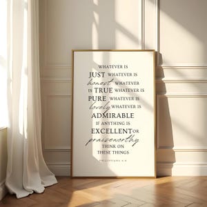 May include: A framed print with a gold border, featuring inspirational text in black. The text includes phrases like "just," "honest," "true," and "lovely." The print is displayed in a well-lit room with a white curtain.