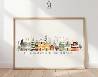 May include: Watercolor print of a festive village scene with colorful houses, trees, and the text "it's the most wonderful time of the year." The artwork is framed in a light wood frame.