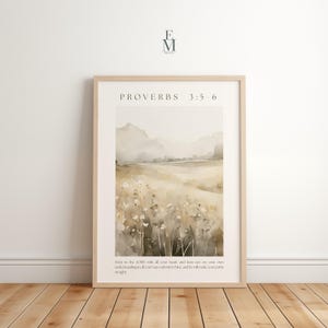 May include: A framed watercolour print depicting a tranquil landscape in soft beige, tan, and grey hues. The artwork includes text from Proverbs 3:5-6. The print is presented in a light wood frame, ideal for home decoration.