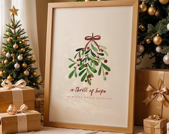 May include: A framed print featuring a watercolor illustration of mistletoe with red berries and a burgundy bow. The text reads "a thrill of hope" and "the weary world rejoices" in a festive font. The frame is light brown.