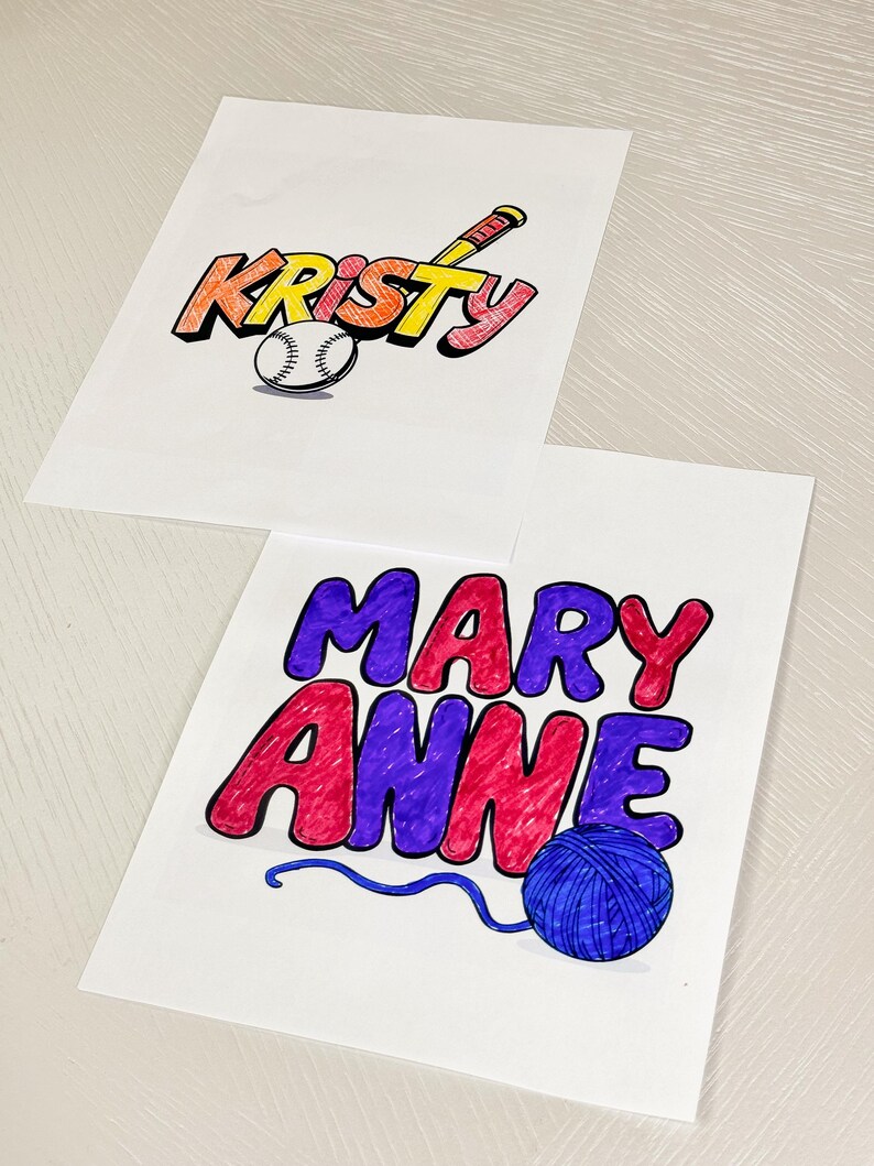 May include: Two personalised name signs, one with the name "Kristy" in yellow, orange, and red with a baseball and bat, and the other with the name "Mary Anne" in purple, red, and blue with a ball of yarn and a blue string.