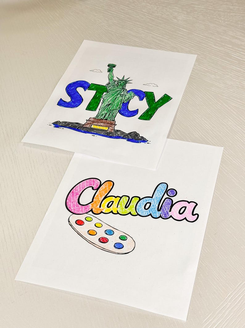 May include: Two personalised colouring pages, one with the name "Stacy" and a drawing of the Statue of Liberty, and the other with the name "Claudia" and a drawing of a paint palette.